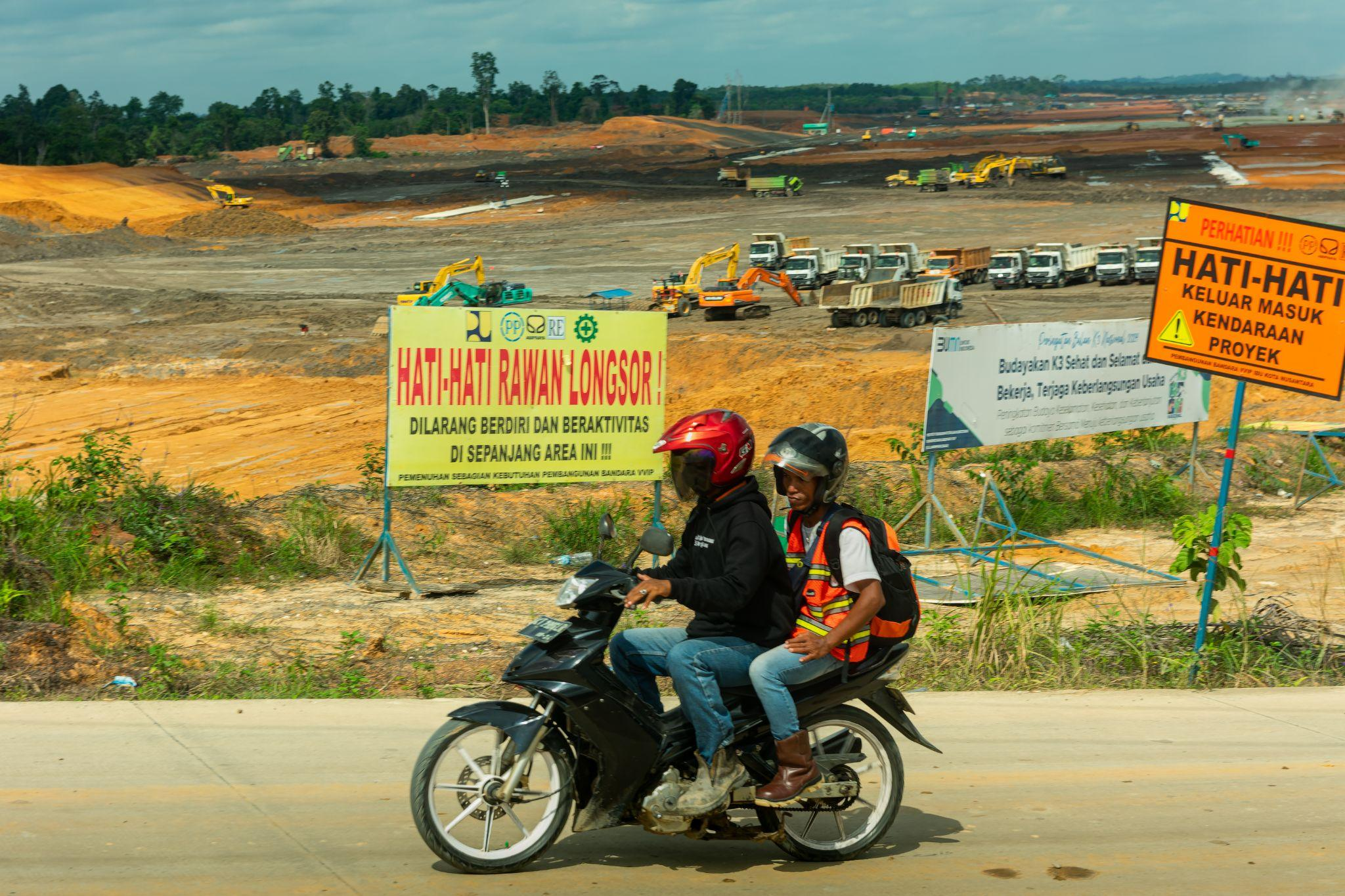 Masyarakat melintas dijalan utama menuju pemukiman ditengah aktivitas pembangunan Bandara Ibu Kota Negara. (FOTO: S. Satria)